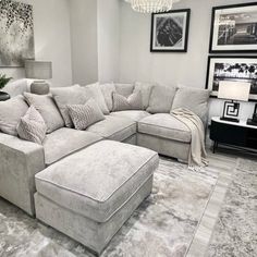 a living room with a large sectional couch and footstool in the middle of it