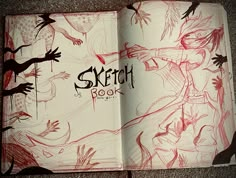 an open sketch book with red ink on the pages and hands reaching out to it