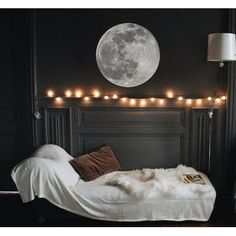 there is a bed with lights on the headboard and a full moon above it