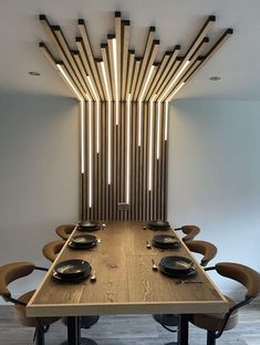 a wooden table with black plates on it and lights hanging from the ceiling behind it