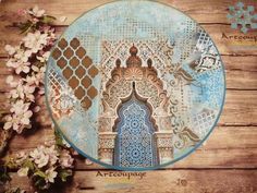 an ornate blue and brown plate with flowers on the wooden table next to it,