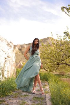 a woman in a long dress standing on a rock