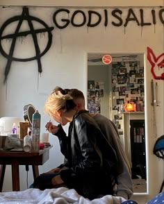 a woman sitting on top of a bed in front of a wall with graffiti writing