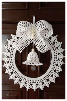 a white crocheted wreath with a bell hanging from it's front door