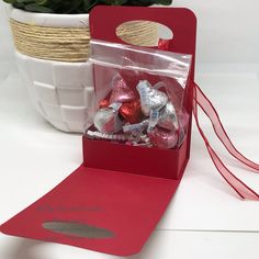 a red box filled with candy next to a potted plant