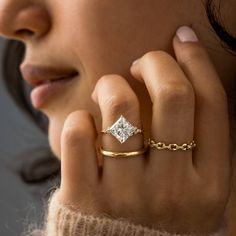 a woman wearing a gold ring with a princess cut diamond on it's finger