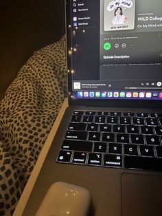 an open laptop computer sitting on top of a bed next to a mouse and blanket