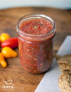 a jar filled with salsa next to some vegetables