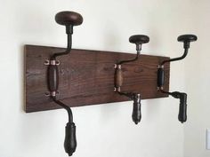 three wooden hooks are attached to the wall with pipe fittings on each one side