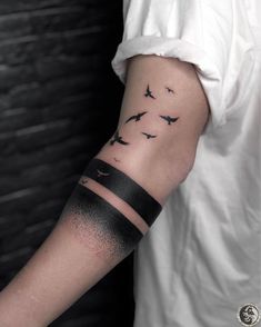 a man's arm with birds flying in the sky on his left forearm and wrist