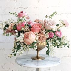 a vase filled with pink and white flowers sitting on top of a marble topped table