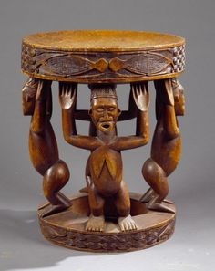 a wooden table with carvings on it and two people sitting under the table holding their hands up