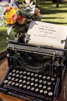 an old - fashioned typewriter with flowers and a note on it sitting on a table