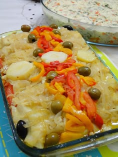 a casserole dish with vegetables and olives in it on a table next to other dishes