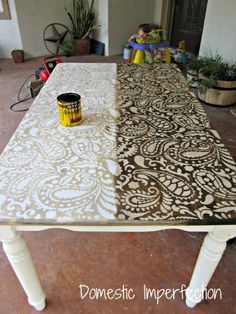 the table is covered with an intricately designed fabric and has a yellow paint can on it