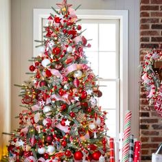 a decorated christmas tree in front of a window with red and white ornaments on it