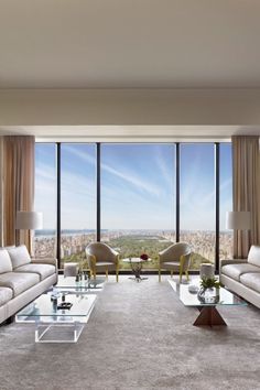 a living room filled with furniture and large windows overlooking a cityscape in the distance