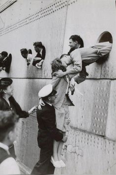 an old black and white photo of people climbing up the side of a building with their hands in each other's pockets