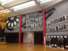 a large room with pictures on the wall and chandelier hanging from the ceiling