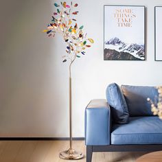 a blue couch sitting next to a tall metal tree on top of a hard wood floor