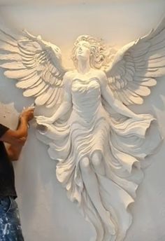 a man is working on an angel sculpture