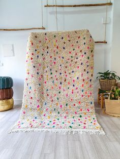 a crocheted blanket with multicolored dots on it in a white room