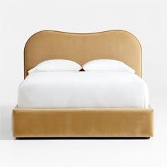 an upholstered bed with white sheets and pillows on the headboard is shown