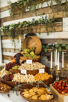 a table topped with lots of different types of foods and desserts next to candles