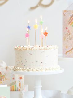 a birthday cake with candles on it sitting in front of some cards and other items