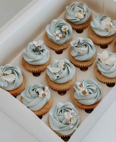 cupcakes in a box with frosting and flowers on the top are ready to be eaten