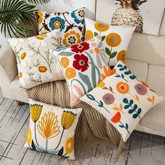 a bunch of pillows sitting on top of a couch next to a potted plant