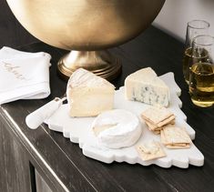 cheese, crackers and wine are sitting on a table next to a gold bowl