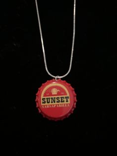 a red bottle cap necklace with the word sunset on it's front and bottom