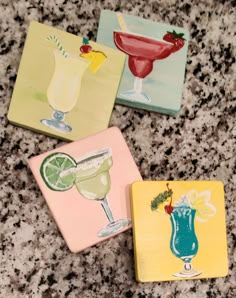 three coasters with different colored drinks on them sitting on a counter top next to each other