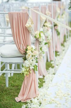 rows of white chairs with pink sashes and flowers lining the aisle at a wedding