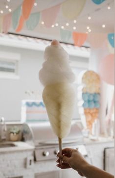 a person is holding an ice cream cone in front of a kitchen with bunting