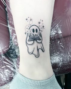 a person with a small tattoo on their ankle that has a ghost reading a book