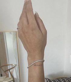 a woman's hand with a diamond bracelet on her wrist and a mirror in the background