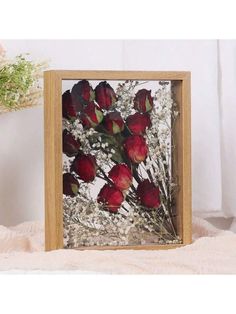 a wooden frame with flowers in it on a white surface next to a flower vase