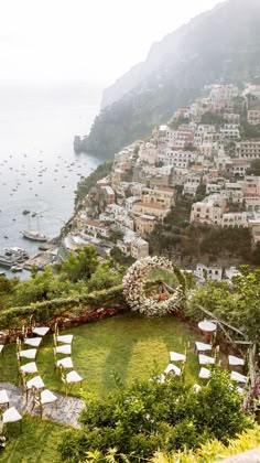 an outdoor ceremony set up on the side of a hill with boats in the water