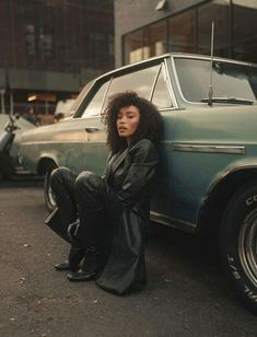 a woman sitting on the ground next to a car