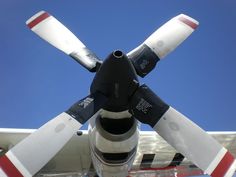 the propeller of an airplane is visible against a blue sky with white and red stripes