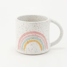 a white coffee mug with a rainbow painted on the side and speckled in gold