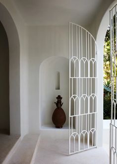 a vase sitting on top of a white shelf next to a wall covered in arches