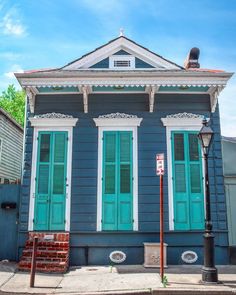 a blue house with green shutters and a street sign in front of the building