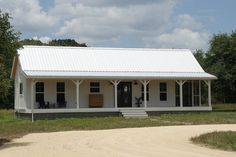 a small white house sitting on top of a dirt road