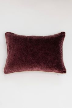 a dark purple velvet pillow on a white background