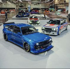 three cars on display at an auto show, one is blue and the other is white