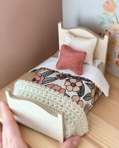 a person is holding up a doll bed