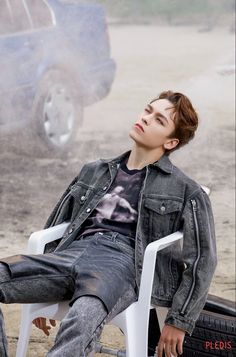 a young man sitting on top of a white chair